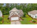 Aerial view of a charming two-story home with a two-car garage, surrounded by lush greenery and well-manicured lawns at 1033 Mccall Loop, Conway, SC 29526