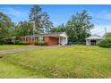 A well-maintained brick home with a carport and detached garage, set on a lush green lawn at 203 Longwood Ln., Conway, SC 29527