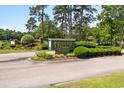Entrance to Heather Lakes neighborhood features lush landscaping, trees, and decorative brick walls at 2567 Lake Vista Dr., Little River, SC 29566