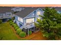 Rear exterior view of a raised beach home featuring a large deck, hammock, and lush landscaping at 6 Indigo Ct., Ocean Isle Beach, NC 28469