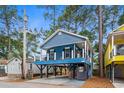 Charming blue two-story coastal home on stilts with a spacious front porch and clear blue sky at 6001 - 1737 S Kings Hwy., Myrtle Beach, SC 29575