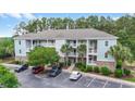 A well-maintained condominium building featuring a lush tree line and multiple parking spaces for residents at 6253 Catalina Dr. # 733, North Myrtle Beach, SC 29582