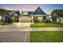 Charming home with a well-manicured lawn, palm tree, and covered porch with white columns at dusk at 1145 Captain Hooks Way, North Myrtle Beach, SC 29582