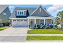 Charming home with a well-manicured lawn and covered porch with white columns and white chairs at 1145 Captain Hooks Way, North Myrtle Beach, SC 29582