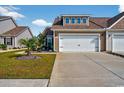Attractive townhome exterior with neat lawn, concrete driveway, and attached garage, bathed in the sun at 1631 Hepburn Dr., Little River, SC 29566