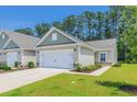 Inviting single-story home with a two-car garage, complimented by lush green grass and a clear blue sky at 2020 Willow Run Dr. # D, Little River, SC 29566