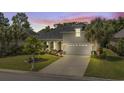 Charming home exterior highlighted by warm lighting, lush landscaping, and a well-maintained lawn at twilight at 2318 Via Palma Dr., North Myrtle Beach, SC 29582