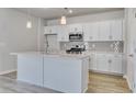 Modern white kitchen with stainless steel appliances, quartz countertops, and an island with a sink at 245 Nw Mayflower Dr., Calabash, NC 28467