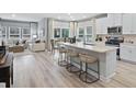 Open-concept kitchen and living room area with hardwood floors, white cabinets, and stainless steel appliances at 2606 Tranquility Loop, Longs, SC 29568