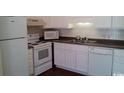 Bright kitchen with white appliances, cabinets, dark countertop, and double stainless steel sink at 411 Cambridge Circle # D4, Murrells Inlet, SC 29576