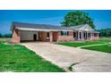 Quaint brick home with a concrete driveway and an attached carport and a well-manicured lawn at 4145 Highway 308, Galivants Ferry, SC 29544