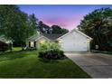 Charming single-story home with brick accents, two car garage, and lush landscaping at dusk at 6887 King Arthur Dr., Myrtle Beach, SC 29588