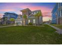 Eye-catching elevation showcases verdant lawn, palm trees, and architectural design elements set against colorful evening sky at 109 Serenity Point Dr., Little River, SC 29566