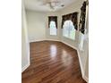 Well-lit living room featuring beautiful hardwood floors and two sunny windows with blinds at 118 Retreat Pl., Little River, SC 29566