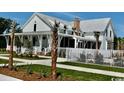 Elegant white farmhouse-style home showcases a large porch, set among manicured lawns and flourishing palm trees at 1741 Tryon Dr, Myrtle Beach, SC 29588