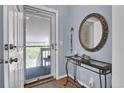 Inviting entryway featuring console table, round mirror, and screen door leading to balcony at 1912 Goose Creek Rd. Sw # 4302, Ocean Isle Beach, NC 28469