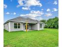Backyard view of a home with gray siding, a covered porch, and a large green lawn at 2599 Woodcreek Ln., Conway, SC 29527