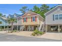 Three beautiful beach homes elevated above ground level and located on a street with lush trees and blue skies at 4319 Grande Harbour Blvd., Little River, SC 29566