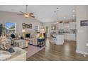 Open-concept living room featuring a vaulted ceiling, fan, wood floors, and a kitchen with white cabinetry at 4319 Grande Harbour Blvd., Little River, SC 29566
