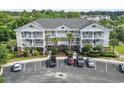 A three-story condo building with white railings and palm trees in front of the parking area at 5801 Oyster Catcher Dr. # 332, North Myrtle Beach, SC 29582