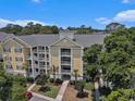 Charming yellow condo building with multiple stories, white balconies, and lush greenery surrounding the property at 601 Hillside Dr. N # 2135, North Myrtle Beach, SC 29582