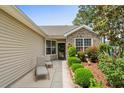 Inviting front porch with seating and a lovely garden featuring lush greenery and colorful flowers around the home's entrance at 675 Vermillion Dr., Little River, SC 29566