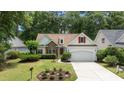 Charming home featuring a stone facade, red shutters, manicured lawn, and an attached two-car garage at 77 Redwing Ct., Pawleys Island, SC 29585