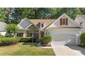 Charming home featuring a stone facade, red shutters, manicured lawn, and an attached two-car garage at 77 Redwing Ct., Pawleys Island, SC 29585