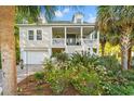 Inviting two-story home featuring a spacious front porch, beautiful landscaping, and a convenient garage at 12 Jerry Ct., Pawleys Island, SC 29585