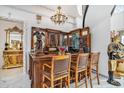 An ornate custom-built wooden bar features stained-glass, statue accents, and three barstools underneath a chandelier at 123 Pioneer Loop, Georgetown, SC 29440