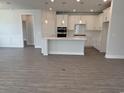 Open-concept kitchen featuring white cabinets, a center island, stainless steel appliances, and wood flooring at 1436 Winding Creek Way, Myrtle Beach, SC 29588