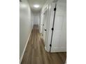 Hallway featuring wood-look flooring and multiple white doors with black hardware at 1509 N Waccamaw Dr. # 112, Murrells Inlet, SC 29576
