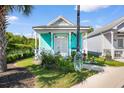 Turquoise house with a cozy front porch, ceiling fans, and beautiful front garden at 230 Addison Cottage Way, Murrells Inlet, SC 29576