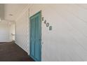 Hallway view of unit 2408 featuring a vibrant turquoise-colored door and white wood paneled walls at 4350 Intercoastal Dr. # 2408, Little River, SC 29566
