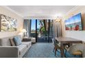 Comfortable living room with a sofa, dining table and chairs, and a sliding glass door to the outdoor balcony at 1105 S Ocean Blvd. # 110, Myrtle Beach, SC 29577