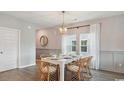 Bright dining room with modern light fixture, wood floors, and seating for six at 147 Warner Crossing Way, Loris, SC 29569