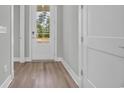 Entryway featuring hardwood floors, a glass-paneled front door, and white trim at 1545 Coastal Cove Ln, Calabash, NC 28467