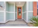 A welcoming front entryway featuring a coral-colored door surrounded by light blue and white accents at 1545 Coastal Cove Ln, Calabash, NC 28467