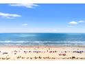 Scenic view of a sandy beach with clear, blue water, beachgoers, and umbrellas under a partly cloudy sky at 2301 S Ocean Blvd. # 1418, Myrtle Beach, SC 29577