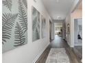 Inviting home hallway with stylish fern artwork, wood-look flooring and a view to the naturally lit living area at 5141 Yellowstone Dr., Conway, SC 29526