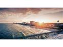 Picturesque beach scene with a long wooden pier and high-rise buildings in the distance at sunset at 814 Night Heron Ln., Myrtle Beach, SC 29572