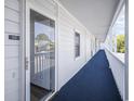 Exterior condo hallway with a blue carpet runner, white railings, and building access entryways at 310 Marsh Pl. # 108, Murrells Inlet, SC 29576