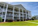 Three-story condo building featuring elevated decks, white columns, and lush landscaping at 5852 Longwood Dr. # 302, Murrells Inlet, SC 29576