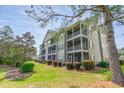 Exterior view of condo featuring screened-in elevated decks, green siding, and lovely landscaping at 5852 Longwood Dr. # 302, Murrells Inlet, SC 29576