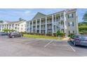 Three-story condo building featuring elevated decks, white columns, and lush landscaping at 5852 Longwood Dr. # 302, Murrells Inlet, SC 29576