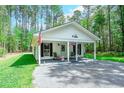 Charming single story house with a covered front porch and gravel driveway surrounded by lush trees at 67 Bossie Ln., Georgetown, SC 29440