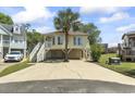 Inviting raised beach home with a palm tree, spacious driveway, and well-maintained landscaping at 914 Dock Pl., Murrells Inlet, SC 29576