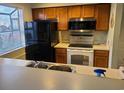 This traditional style kitchen features wood cabinets, black appliances, a dual basin sink, and a window at 1025 W Plantation Dr. W # 2817, Little River, SC 29566
