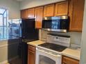 Traditional kitchen featuring oak cabinets, a black refrigerator, white oven, stainless steel microwave, and light countertops at 1025 W Plantation Dr. W # 2817, Little River, SC 29566