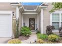Inviting front entrance with a decorative door, stylish lighting, and lush landscaping, creating a warm and welcoming ambiance at 15 Saltwind Loop, Murrells Inlet, SC 29576
